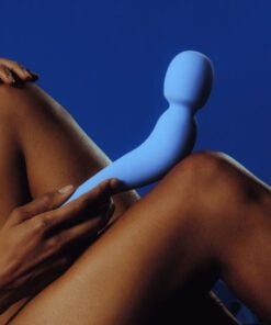 Dame Com Wand Vibrator in Periwinkle resting on a knee