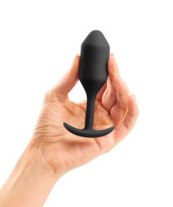 Hand holding a medium sized, black Snug Plug butt plug covered withÂ  silicone on a white background